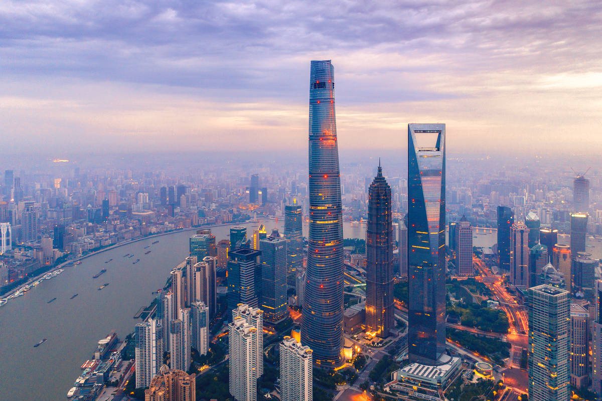 Vista aérea de los rascacielos de Pudong en Shanghai al atardecer, con la Shanghai Tower, la Torre Jin Mao y el río Huangpu
